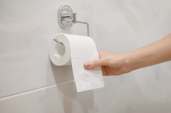 A woman takes toilet paper from a roll of toilet paper in the toilet. Close-up. The concept of problems with the intestines, cystitis.