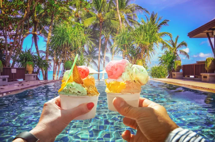 Couple with beautiful bright  sweet Italian ice-cream with different flavors  in the hands  . Background of  panoramic view of tropical beach with coconut palm trees. Koh Samui, Thailand