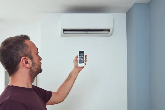 Man holding a modern AC unit remote.