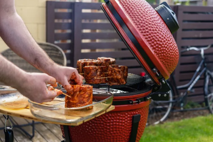 Red Ceramic Barbecue Grill. Grilling, Smoking, Baking, BBQ and Roasting process. Post-quarantine Picnic in modern homes terrace.