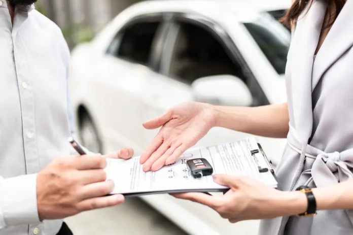 Automotive business, car sale or rental concept : Happy customer with car dealer agent making deal and signing on agreement document contract in auto showroom or car dealer office.