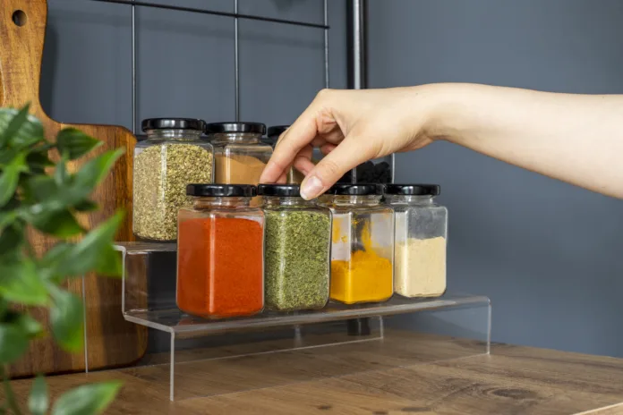 Cropped hand holding jar of spices on kitchen.