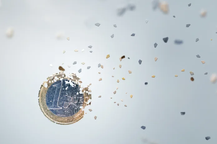 Economic concept. One Euro Coin breaking into small pieces. Isolated on neutral background.