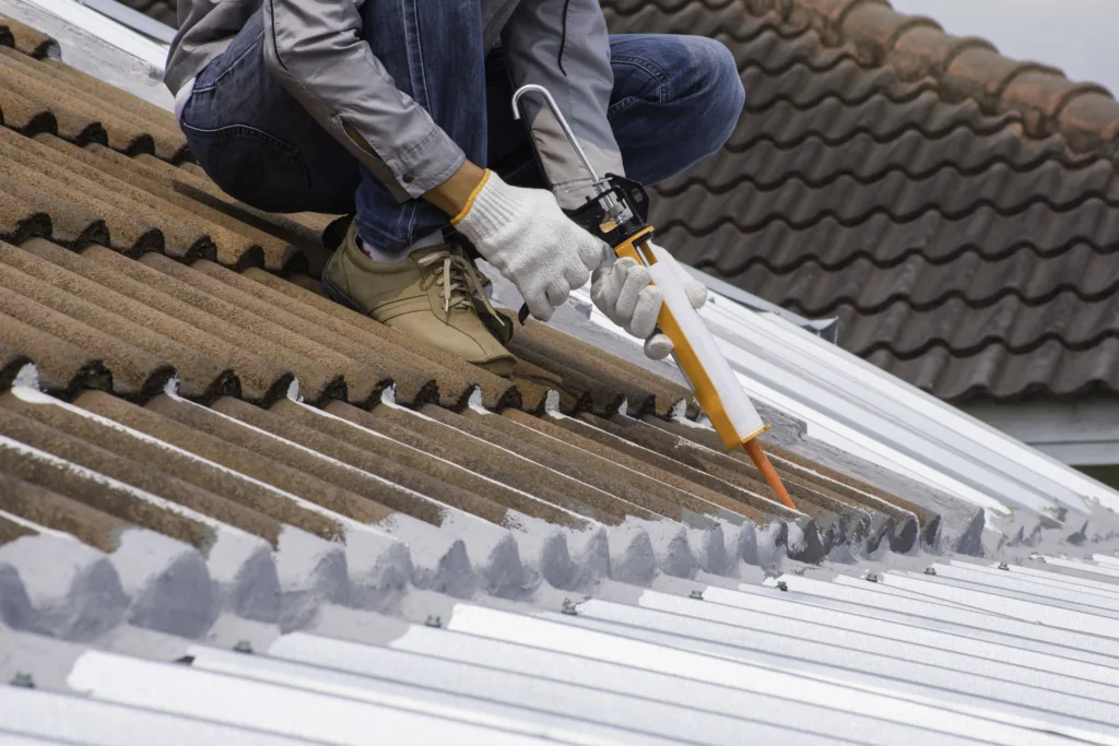 Technician man hand using glue gun with silicone adhesive or manual caulking gun with polyurethane to seal the leak on the roof. Installing and building construction concept.