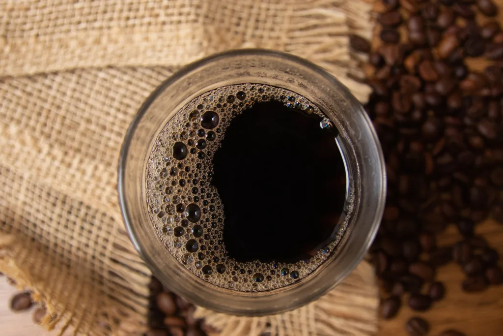 Top view of cup of hot coffee in American glass, traditional breakfast in brazil. background with jute and coffee beans