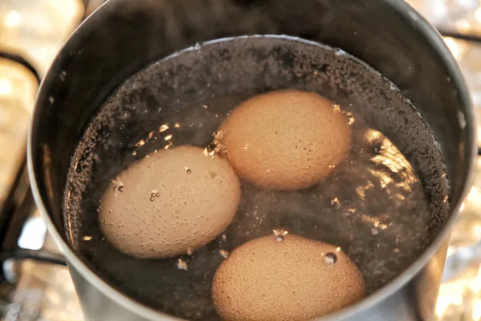 Eggs in the pan boiling with water bubbles cooking.