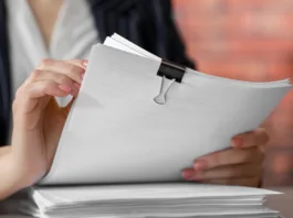 Woman stacking documents at table in office, closeup