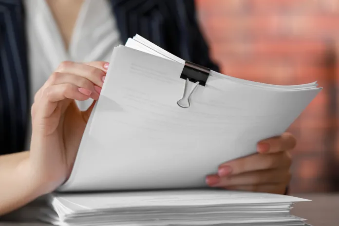 Woman stacking documents at table in office, closeup