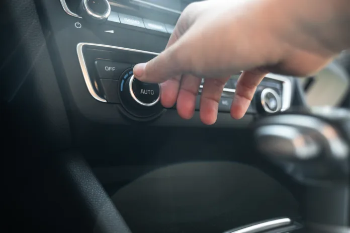 Close-up of hand using temperature control knob on car dashboard from driver side