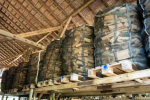 Pallet stacked and ready packaged piles of firewood stored in a barn, no people.