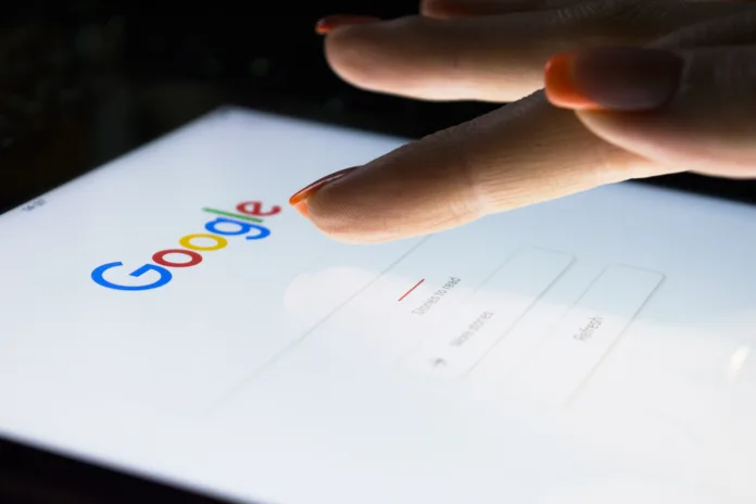 Sankt-Petersburg, Russia, November 8, 2017:  A woman's hand is touching screen on tablet computer iPad Pro at night for searching on Google search engine. Google is the most popular Internet search engine in the world. Photo taken at company office.