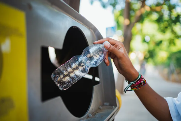 Close up shot of a woman's hand holding a empty plastic bottle to throw it into the trash