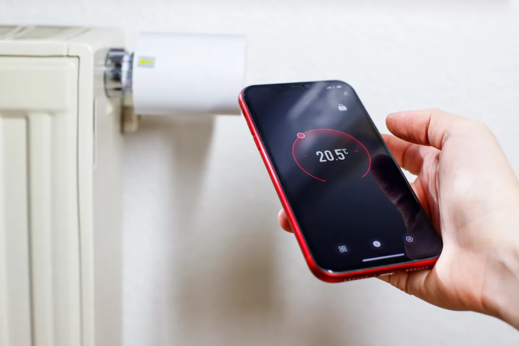 Controlling radiator heating temperature with a smart phone, close-up with radiator on the background. Concept of a smart home and mobile application for managing smart devices at home