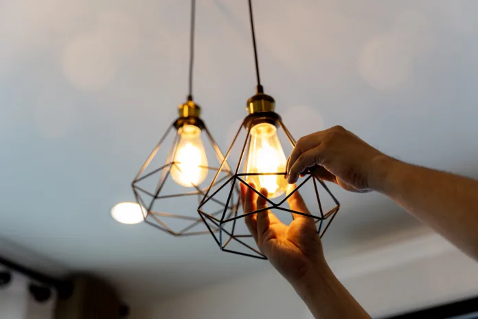 Electric LED Lightbulb Change In Light At Home. Decorative antique edison style filament light bulbs hanging. An electrician is installing spotlights on the ceiling