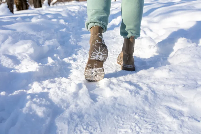 Feet in winter boots walking on crisp, fresh snow. Walking on snow with winter boots. Warm clothes. Close-up.