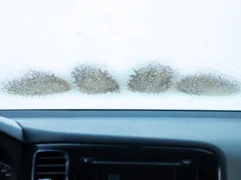 frozen car windshield in winter, inside the car, cold temperature, melting ice on the window, working climate control. Close-up photo with copy space