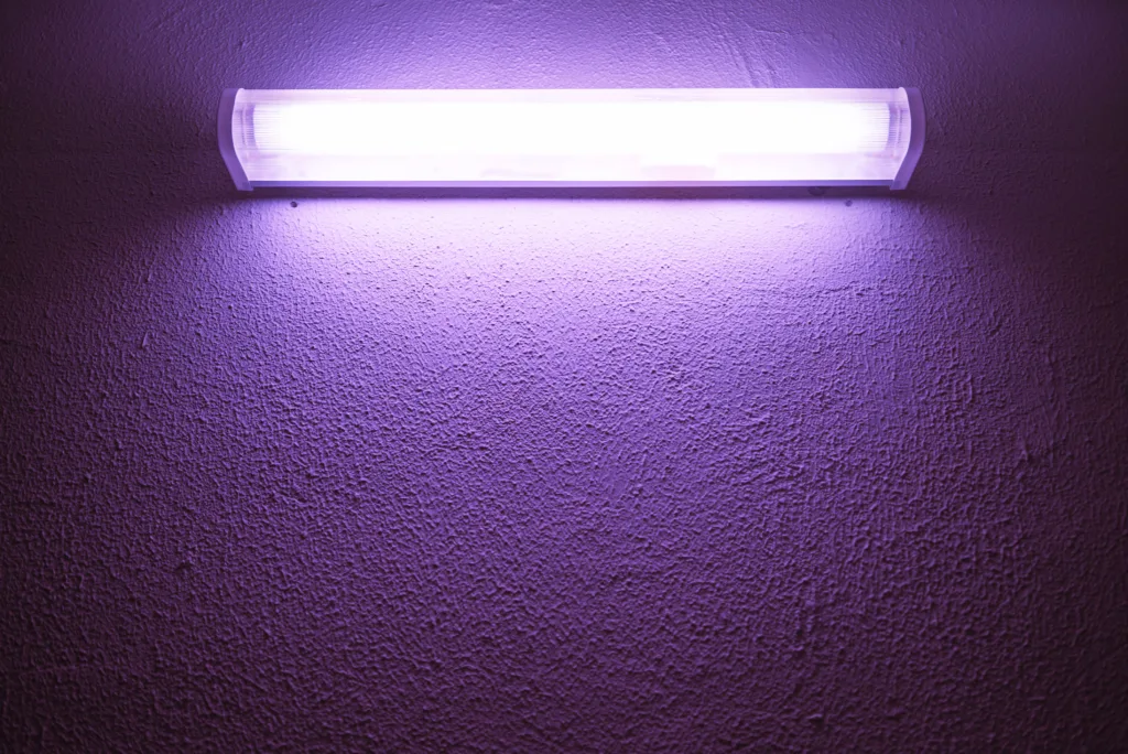 Germicidal ultraviolet lamp glows on a rough wall