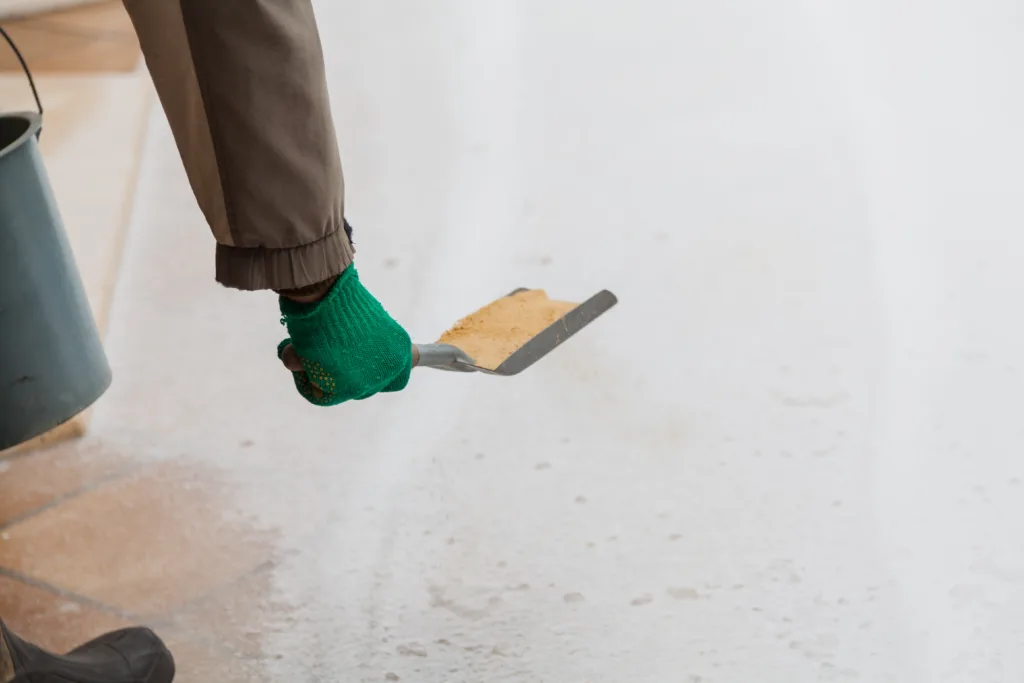 Injury prevention. Hand in a green glove sprinkles sand on a winter track with a small shovel