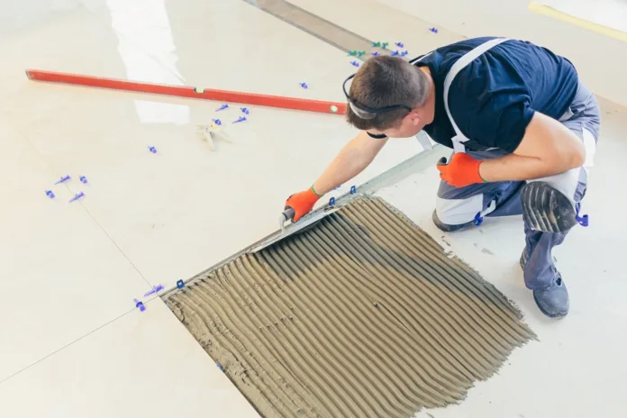 A male construction worker installs a large ceramic tile