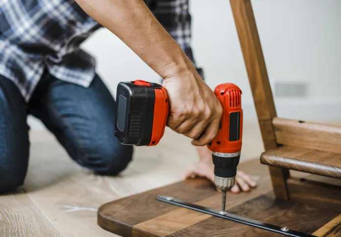 Man using hand drill to assemble a wooden table