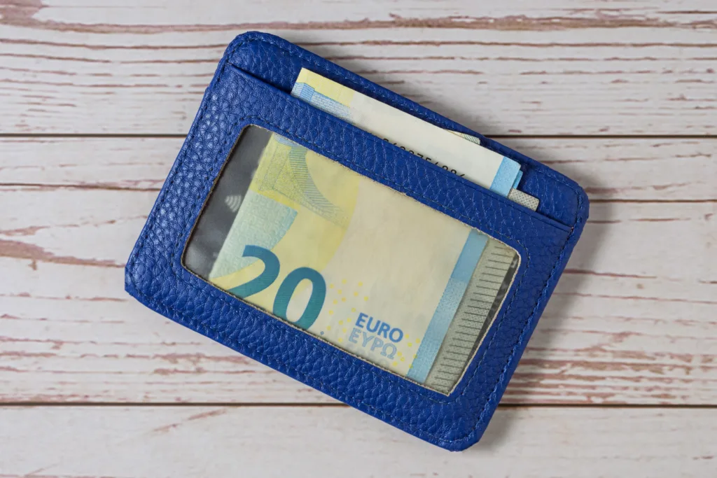 Top view of a blue transparent wallet with Euro 20 bills on a wooden background. Close-up